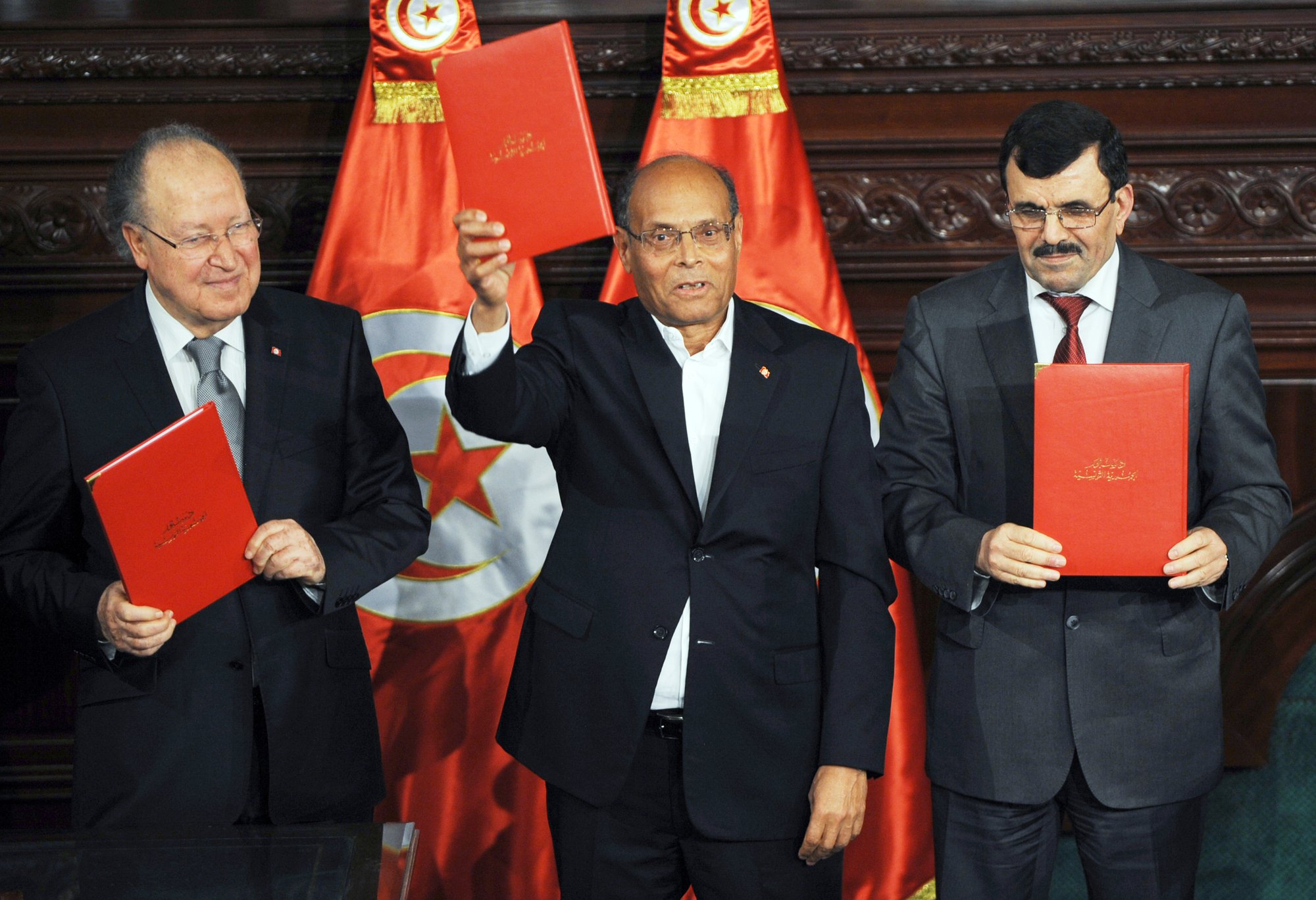 Brandissant la nouvelle Constitution, aux côtés de Mustapha Ben Jaafar (à g.) et Ali Larayedh, le 27 janvier 2014. © fethi belaid/AFP