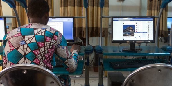 Un homme surfe sur internet dans un cyber-café de Cotonou, au Bénin, le 24 février 2016. © Gwenn Dubourthoumieu pour Jeune Afrique
