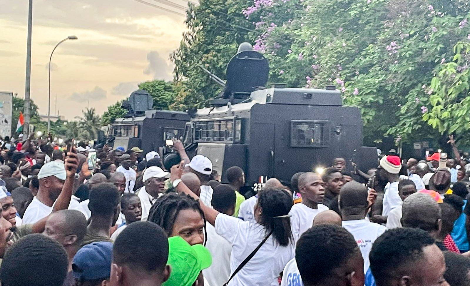 Des blindés des forces de l’ordre au milieu de la foule de partisans de Laurent Gbagbo, près du QG du FPI à Attoban, le 17 juin 2021, au moment de l’arrivée de l’ancien président ivoirien. © Photo : Vincent Duhem pour JA