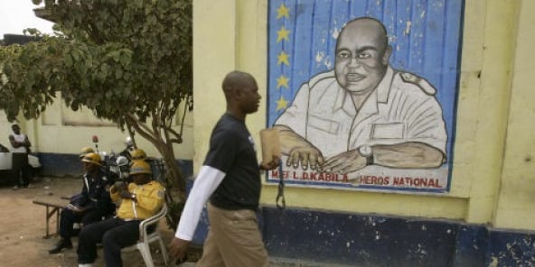 Un Cogolais passe devant un portrait mural de Lauren-Désiré Kabila, le 9 août 20016 à KInshasa.