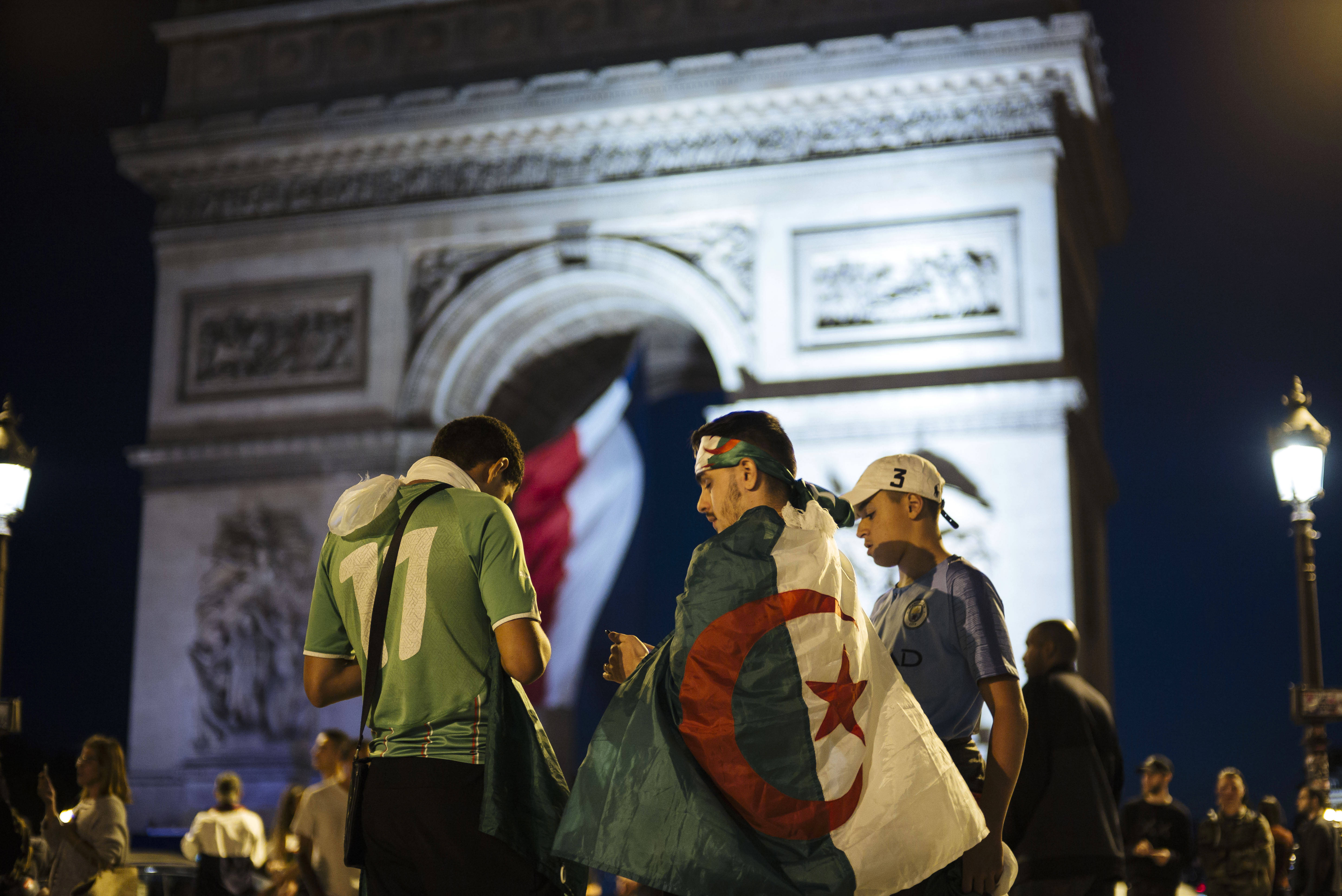 Des supporteurs de football arborant le drapeau algérien devant l'Arc de Triomphe, à Paris, dimanche 14 juillet après la victoire des Fennecs en demi-finale de la CAN.