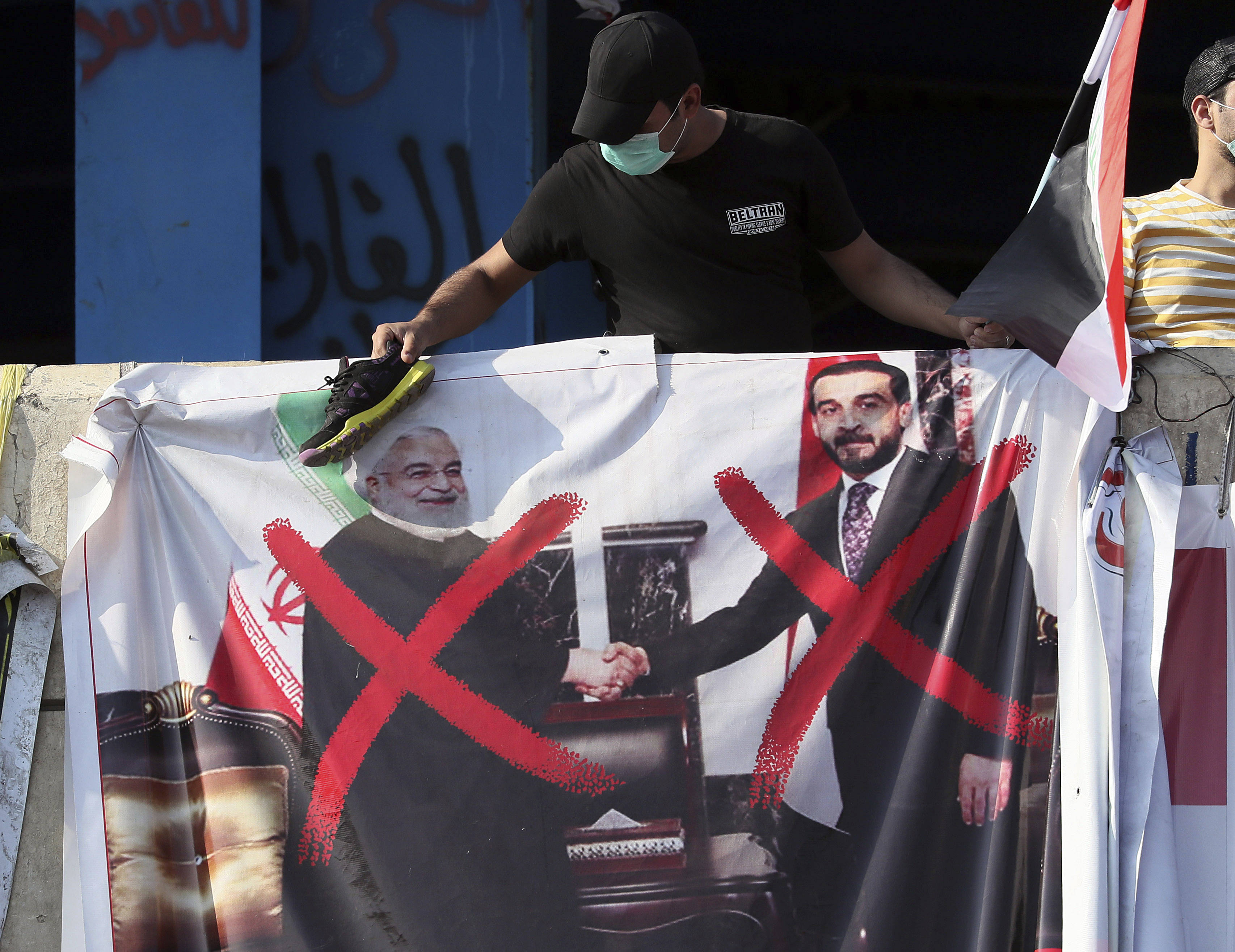 Une affiche du président du Parlement irakien, Mohammed al-Halbousi, à droite, et du président iranien, Hassan Rohani, à gauche, est suspendue à un bâtiment situé près de la place Tahrir, lors des manifestations en cours à Bagdad, en Irak, mercredi 6 novembre 2019.