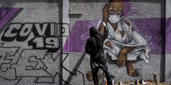 Un artiste graffeur peint un message de prévention contre le coronavirus, dans les rues de Dakar, le 25 mars 2020.