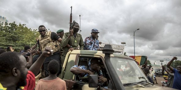 Des manifestants saluent le passage un convoi de militaires à Bamako, le 19 août 2020, au lendemain de la démission d'IBK.