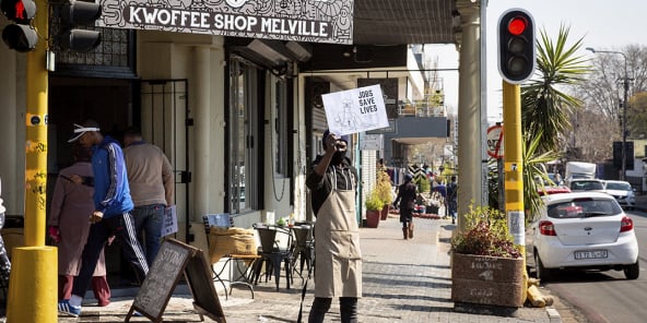 Un homme tient un panneau sur lequel est écrit « Les emplois sauvent des vies » à l’extérieur d’un restaurant à Johannesburg, en Afrique du Sud, le 22 juillet 2020.