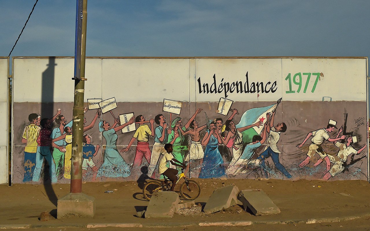 Un enfant passé à vélo devant un graffiti célébrant l'indépendance de Djibouti, en 1977, à Djibouti, le 4 mai 2015. © CARL DE SOUZA/AFP.